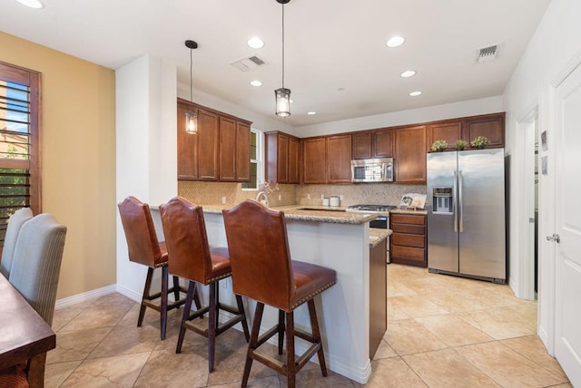 kitchen with light stone countertops, decorative light fixtures, stainless steel appliances, tasteful backsplash, and kitchen peninsula