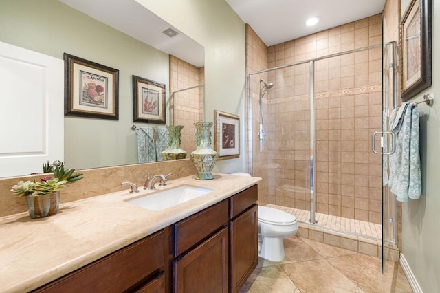 bathroom with a shower with shower door, vanity, tile patterned floors, and toilet