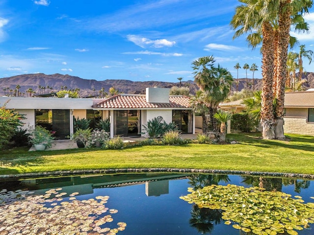 rear view of property featuring a water and mountain view and a yard