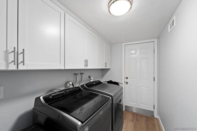 laundry area featuring cabinets, separate washer and dryer, and dark hardwood / wood-style flooring