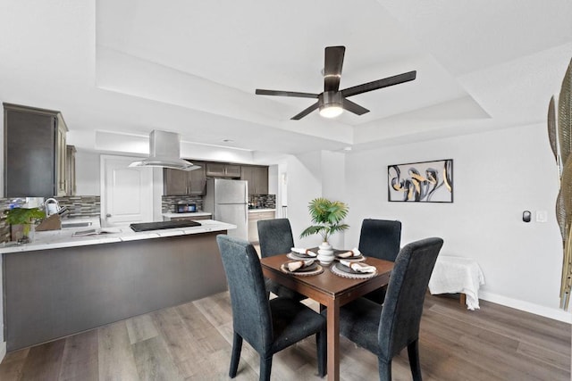 dining room featuring ceiling fan, hardwood / wood-style flooring, and a tray ceiling