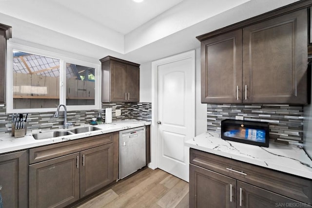 kitchen with sink, light wood-type flooring, light stone counters, stainless steel dishwasher, and dark brown cabinets