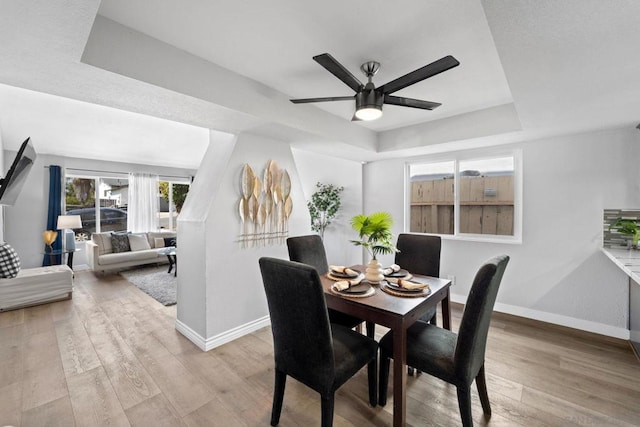 dining area featuring ceiling fan, a tray ceiling, and hardwood / wood-style floors