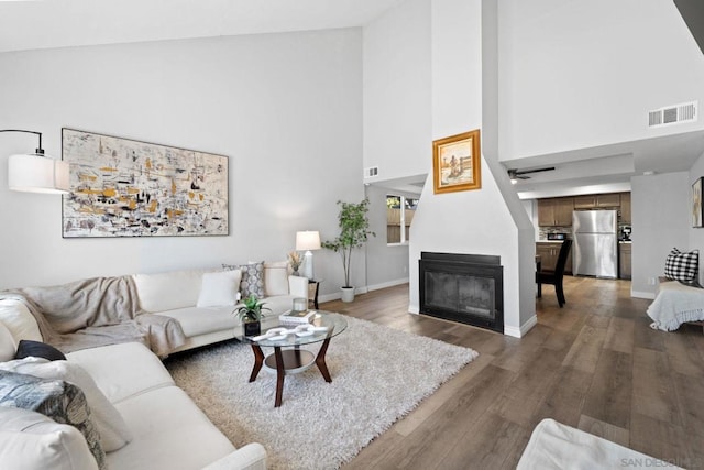 living room with a large fireplace, dark hardwood / wood-style floors, and high vaulted ceiling