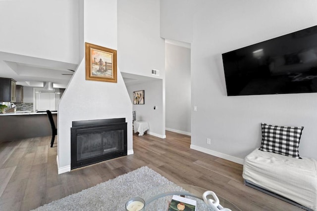 living room with dark wood-type flooring, a towering ceiling, and a fireplace