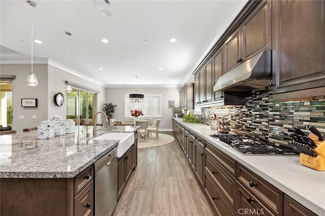 kitchen with pendant lighting, appliances with stainless steel finishes, dark brown cabinetry, sink, and backsplash