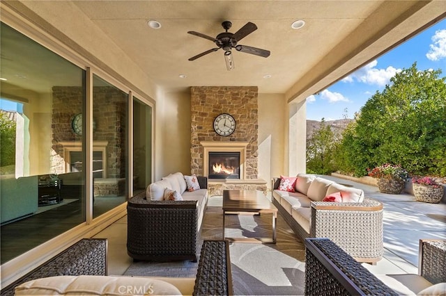 view of patio / terrace with ceiling fan and an outdoor living space with a fireplace