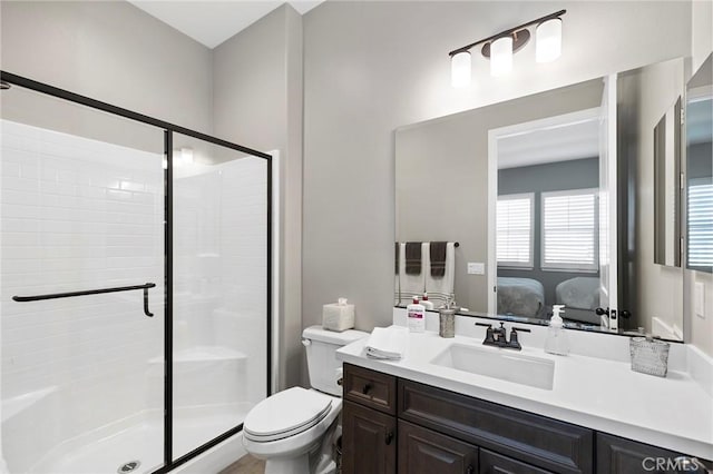 bathroom featuring toilet, vanity, and a shower with shower door