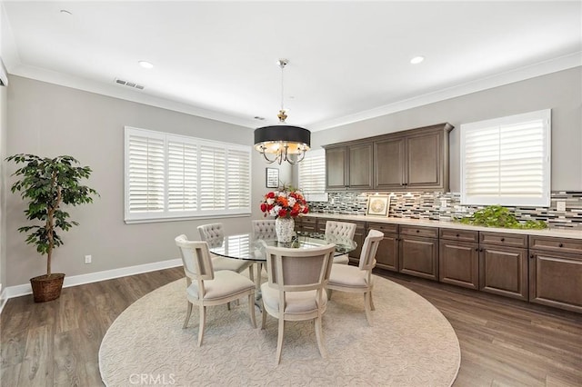 dining room with an inviting chandelier, ornamental molding, and dark hardwood / wood-style floors