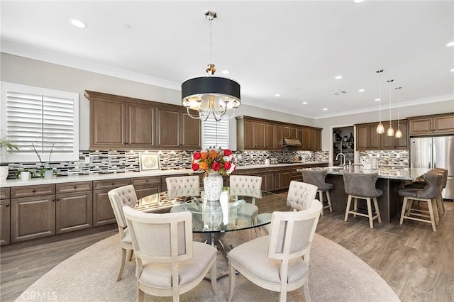 dining room featuring dark wood-type flooring, sink, an inviting chandelier, and ornamental molding