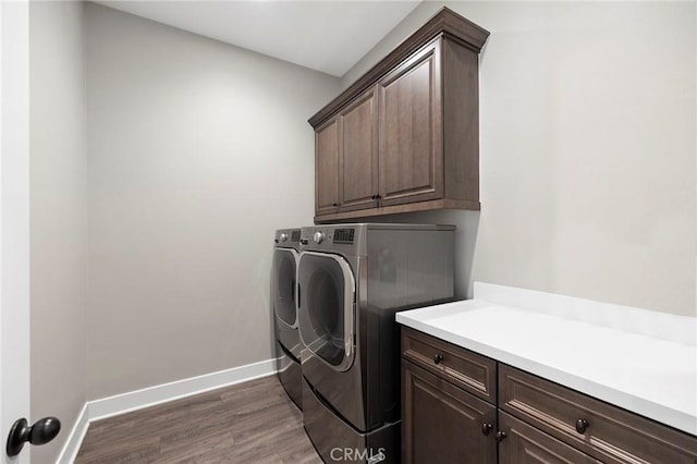 laundry area featuring dark hardwood / wood-style floors, washer and dryer, and cabinets