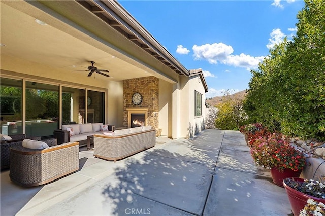 view of patio featuring ceiling fan and an outdoor living space with a fireplace