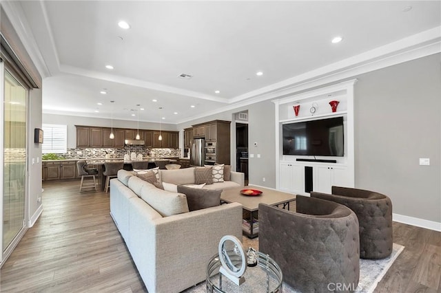 living room featuring ornamental molding, light hardwood / wood-style floors, and a tray ceiling