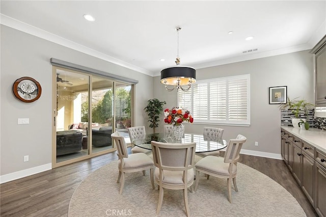 dining area with dark hardwood / wood-style floors, crown molding, and a chandelier