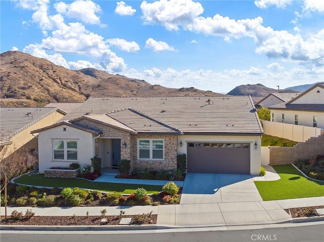 ranch-style home featuring a mountain view, a front yard, and a garage