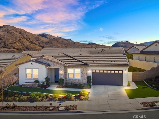 view of front of home with a mountain view, a garage, and a lawn