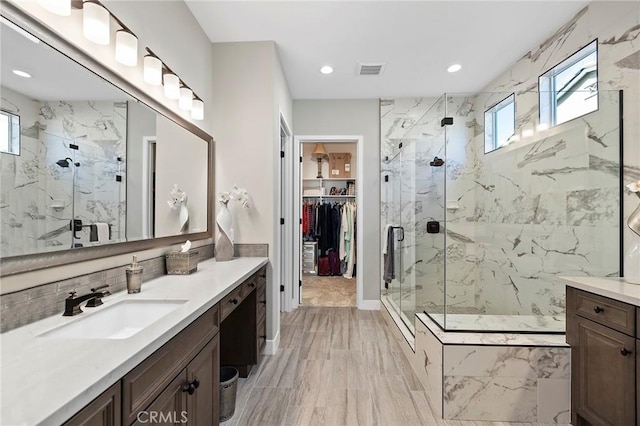 bathroom with a shower with shower door, vanity, and tasteful backsplash