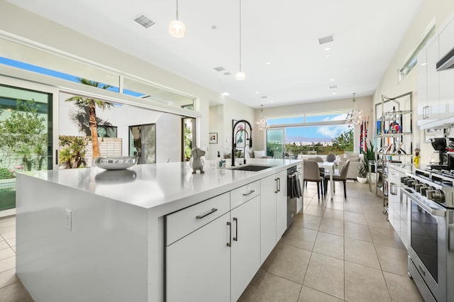 kitchen featuring sink, white cabinetry, hanging light fixtures, an island with sink, and stainless steel appliances