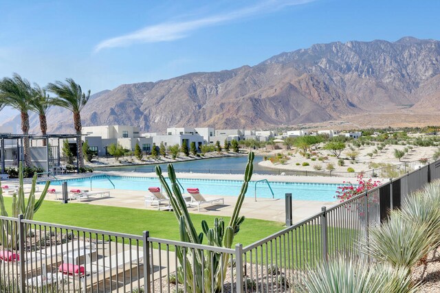 view of swimming pool with a mountain view and a lawn