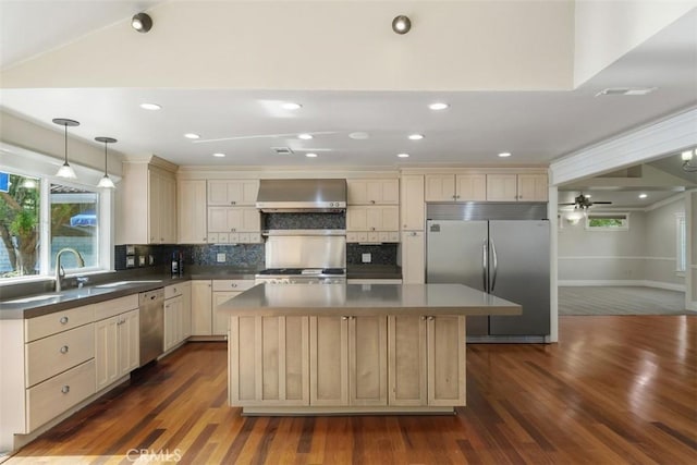 kitchen with a kitchen island, decorative light fixtures, tasteful backsplash, stainless steel appliances, and wall chimney range hood