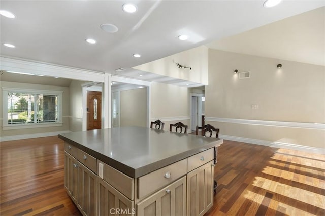 kitchen with vaulted ceiling, a center island, and dark wood-type flooring