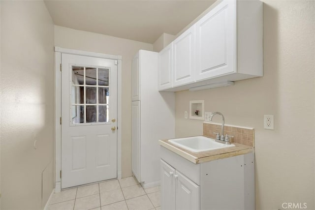 washroom with cabinets, light tile patterned flooring, sink, and washer hookup