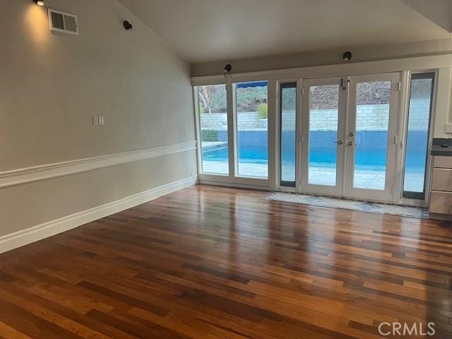 spare room featuring dark hardwood / wood-style flooring, vaulted ceiling, and french doors