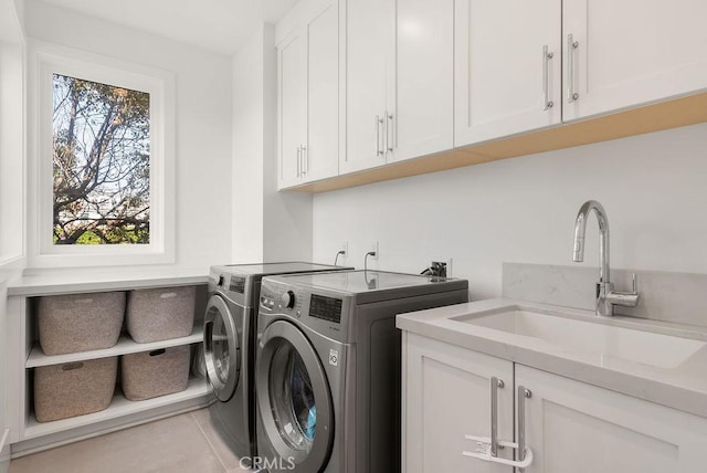 clothes washing area with light tile patterned flooring, cabinets, separate washer and dryer, and sink