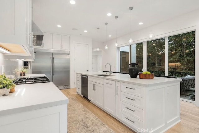 kitchen featuring hanging light fixtures, white cabinetry, a kitchen island with sink, and stainless steel appliances