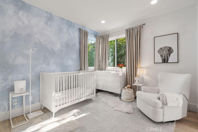 bedroom featuring hardwood / wood-style flooring and a crib