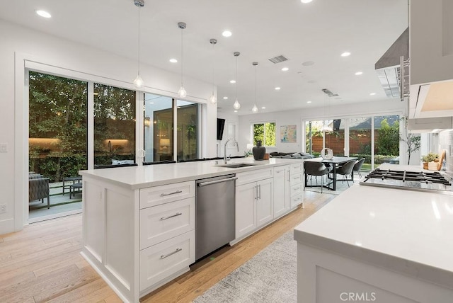 kitchen featuring a kitchen island, pendant lighting, white cabinetry, sink, and stainless steel appliances