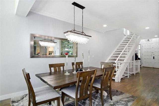 dining space featuring dark wood-type flooring, crown molding, and a notable chandelier