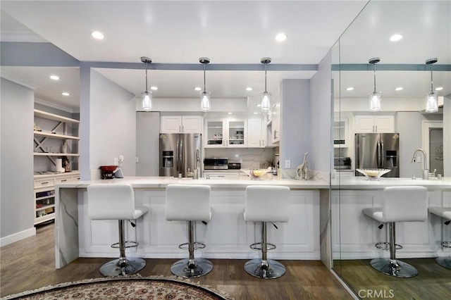 kitchen featuring white cabinets, a kitchen bar, and stainless steel fridge