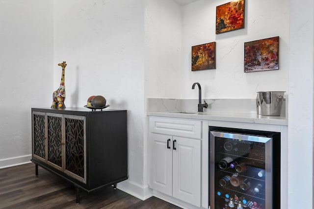 bar with sink, white cabinets, dark wood-type flooring, and beverage cooler