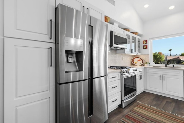 kitchen with sink, white cabinets, dark wood-type flooring, backsplash, and stainless steel appliances