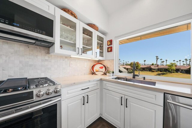 kitchen with dark hardwood / wood-style flooring, sink, backsplash, white cabinetry, and stainless steel appliances