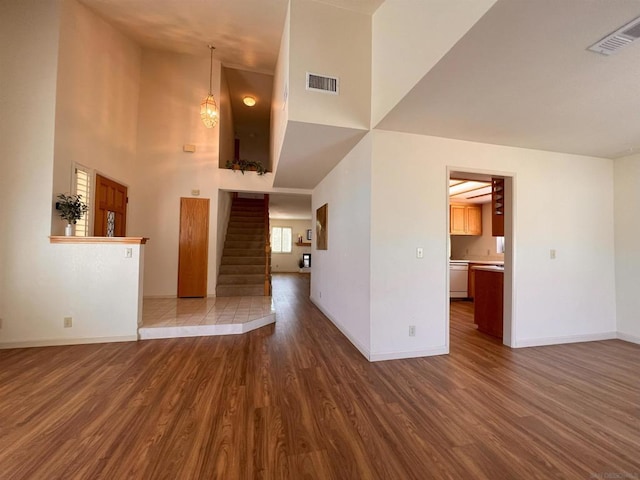 unfurnished living room featuring a towering ceiling and dark hardwood / wood-style floors