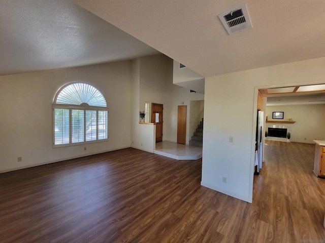 unfurnished living room with a textured ceiling, dark hardwood / wood-style flooring, and a tiled fireplace