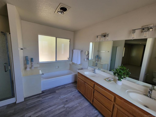 full bathroom with toilet, vanity, hardwood / wood-style floors, plus walk in shower, and a textured ceiling