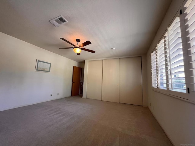 unfurnished bedroom with light carpet, ceiling fan, and a closet