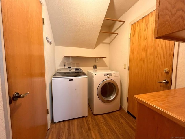 clothes washing area with cabinets, washing machine and dryer, a textured ceiling, and light hardwood / wood-style flooring