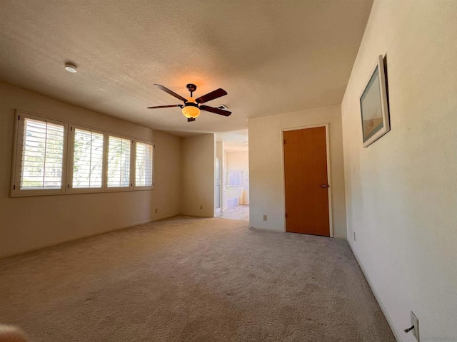 carpeted empty room featuring ceiling fan and a textured ceiling