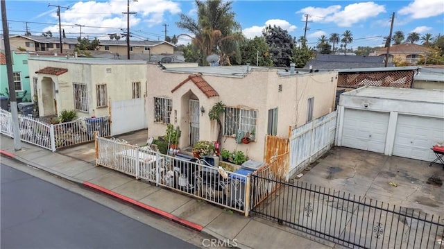 exterior space featuring a garage, concrete driveway, a fenced front yard, and stucco siding