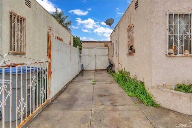 exterior space featuring a gate, a patio area, fence, and stucco siding