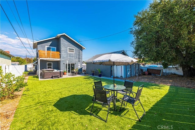 rear view of property with a lawn, a swimming pool with hot tub, and a balcony