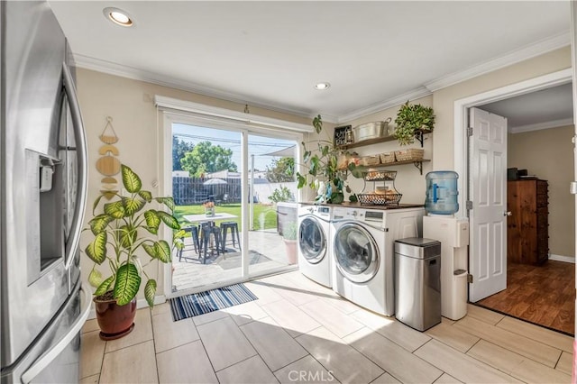 clothes washing area with crown molding, light wood-type flooring, and separate washer and dryer