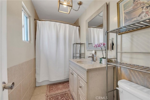 bathroom with toilet, vanity, tile walls, and tile patterned floors