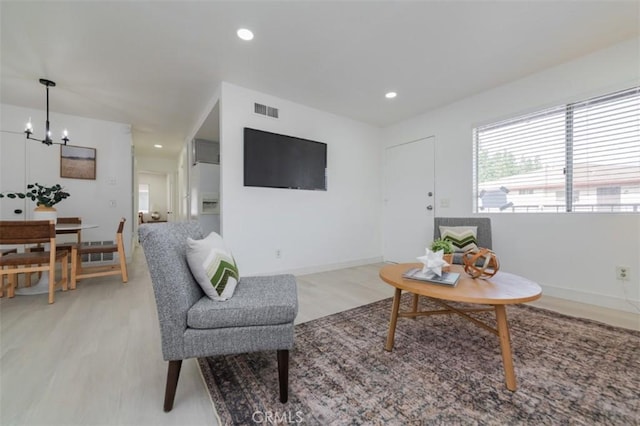 living room with an inviting chandelier and light hardwood / wood-style floors