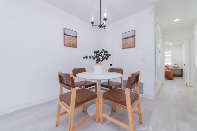 dining room with light wood-type flooring and a notable chandelier