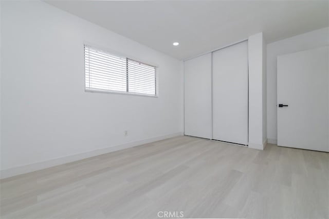 unfurnished bedroom featuring light wood-type flooring and a closet